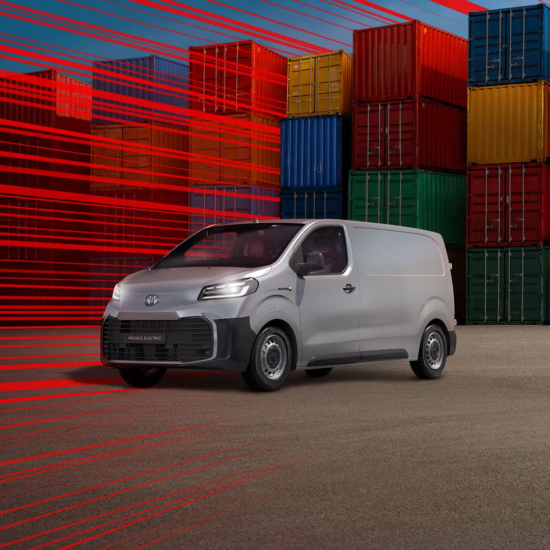 Ein grauer Proace Electric steht umgeben von Holz-Paletten an einer Ladesäule.